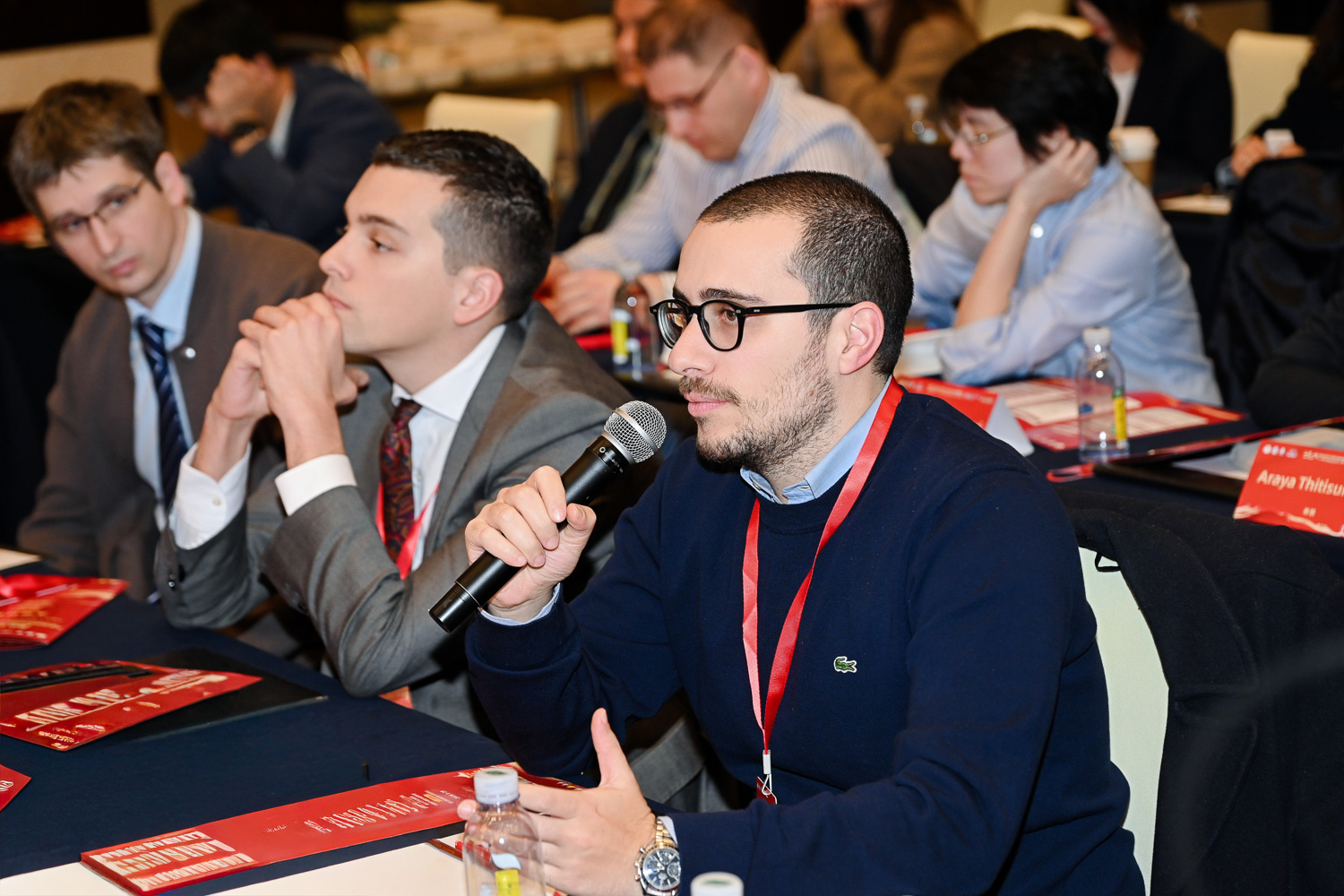 2026年一带一路肝脏微创技术国际培训班启动仪式现场，外籍专家在讲台发表演讲，身后红色背景板展示丝路同心创新共行主题，四川大学华西医院主办，成都高端医疗学术会议演讲抓拍摄影案例